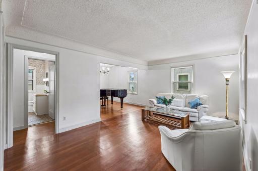 Spacious main-level living room featuring hardwood floors, abundant natural light, and an open connection to the adjacent dining/flex space.