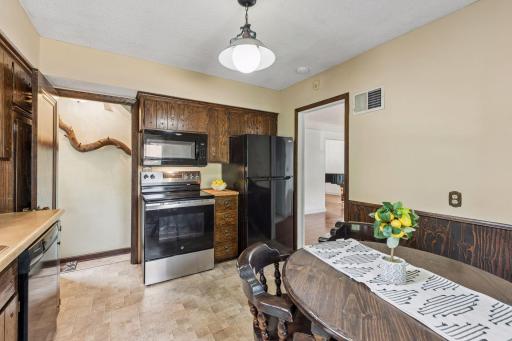 Functional kitchen with newer range, refrigerator, microwave, dishwasher, abundant cabinetry, and space for a breakfast table.