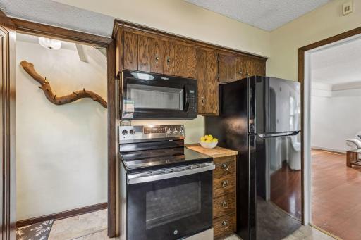Additional kitchen view highlighting the newer range, appliance storage, cabinetry, convenient connection to the main-level living spaces and access to the lower level.