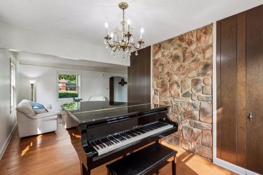 Dining room currently arranged as a piano room, highlighted by a distinctive stone accent wall and hardwood floors. Easily returned to traditional dining use.