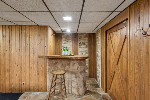 Built-in bar adds character and entertaining space to the finished lower level, complemented by stone details and warm wood finishes.