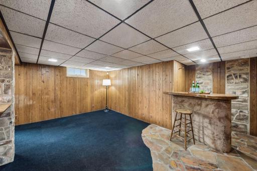 Spacious finished lower-level family room with built-in bar, stone accents, and plenty of space for recreation, entertaining, or a media area.