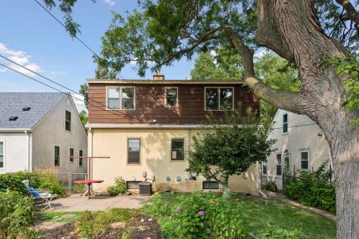 Backyard with mature trees, established landscaping, an apple tree, berry bushes, and plenty of space for flowers and gardening.