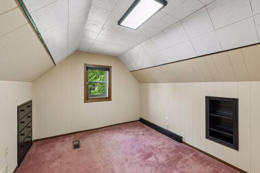 Another upper-level bedroom with a window, built-in storage, and charming sloped ceilings.