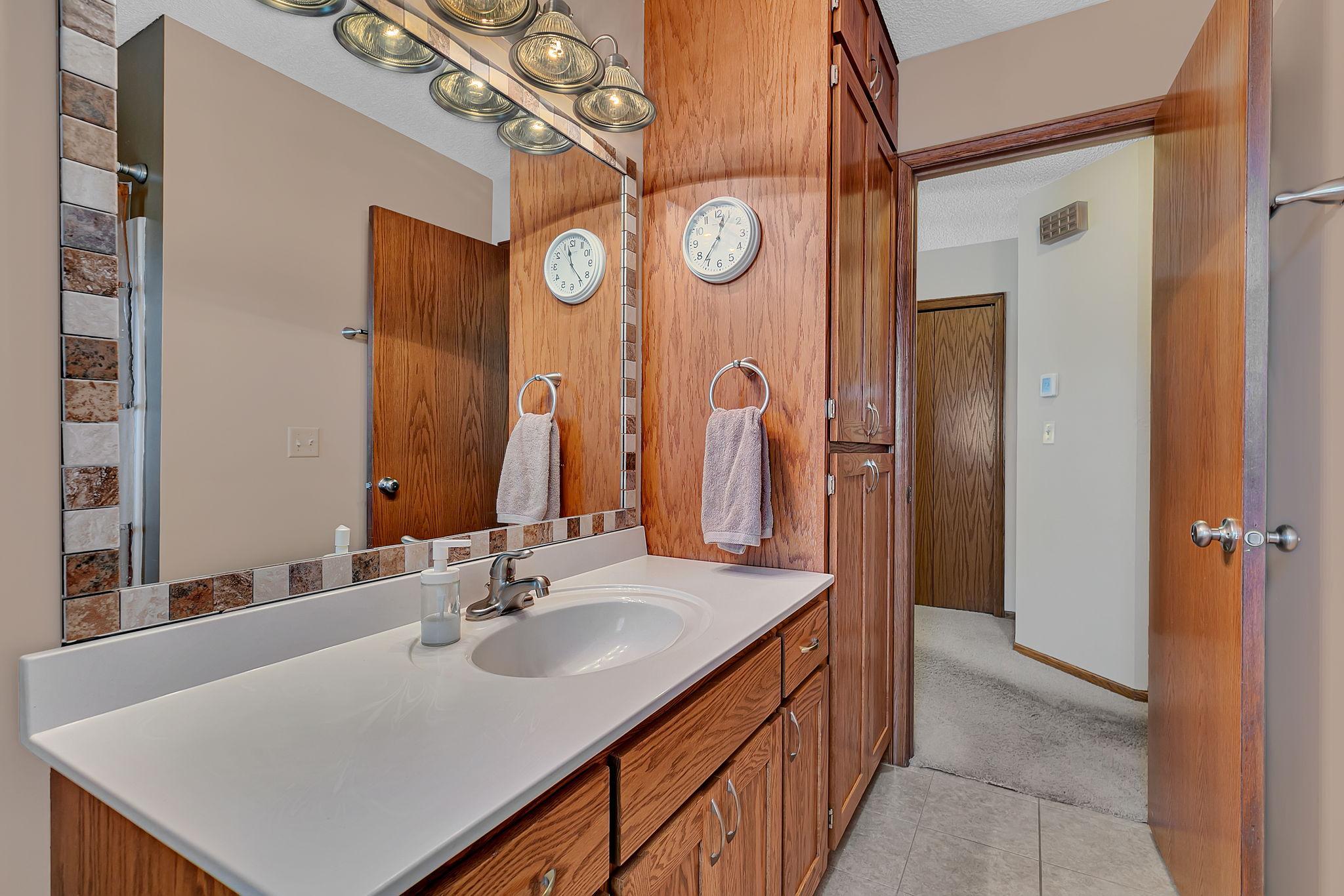 The upper-level full bath features a spacious vanity and a stylish decorative mirror surround, adding both function and character to the space.