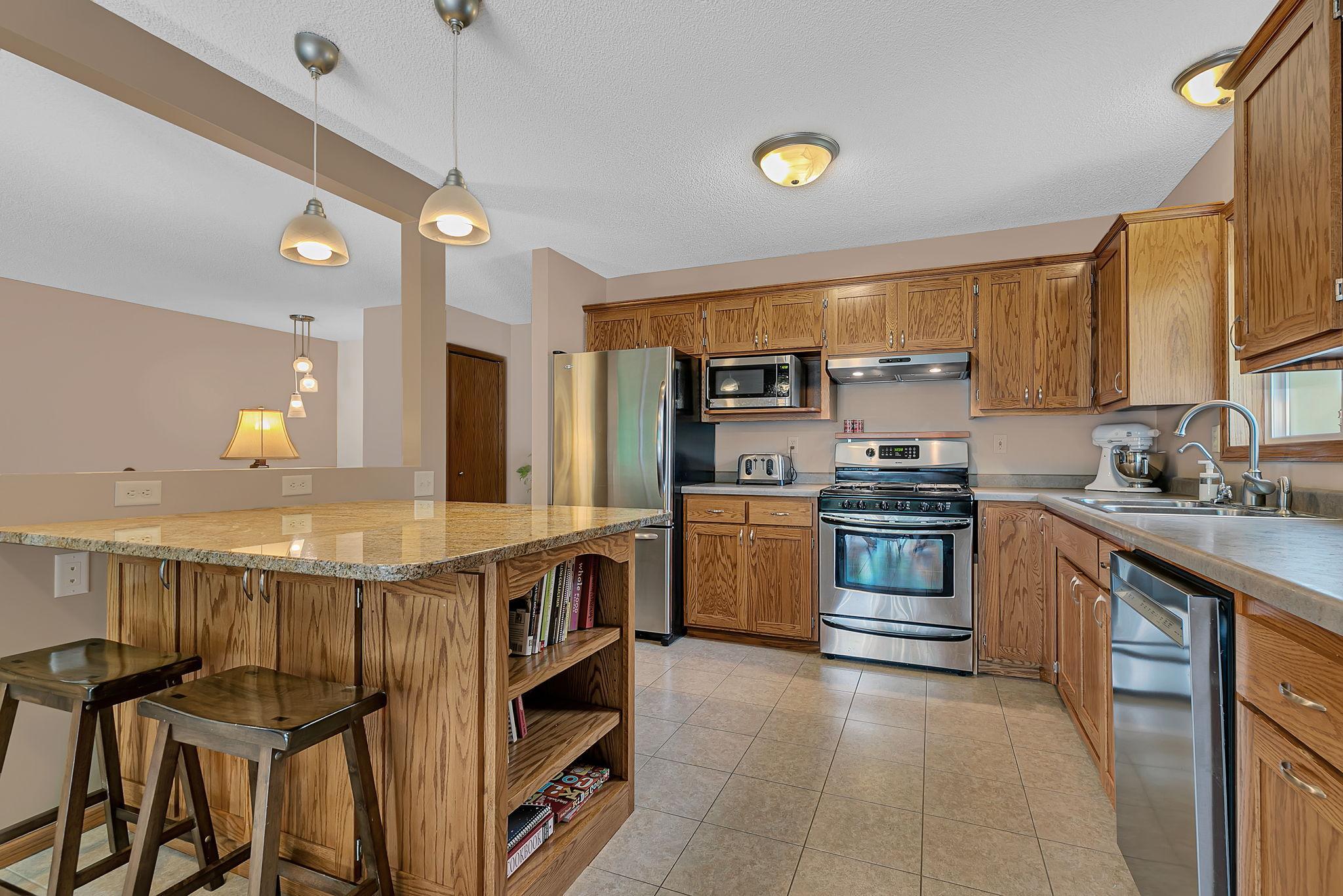 An updated kitchen with a spacious center island, ample cabinet and countertop space, stainless steel appliances, and a gas range. Open sightlines to the living room create a connected space perfect for everyday living and entertaining.