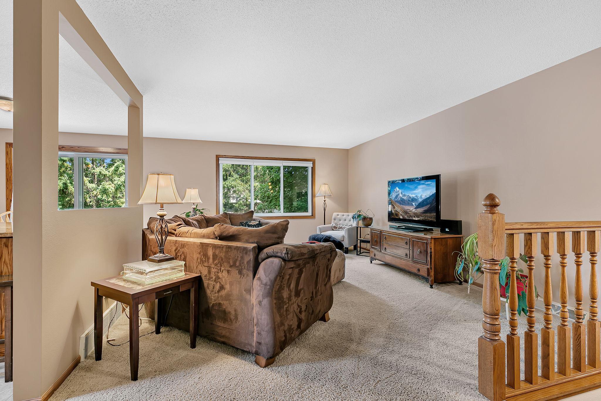 An inviting living room filled with natural light from the windows and an open-concept layout that flows seamlessly into the kitchen.