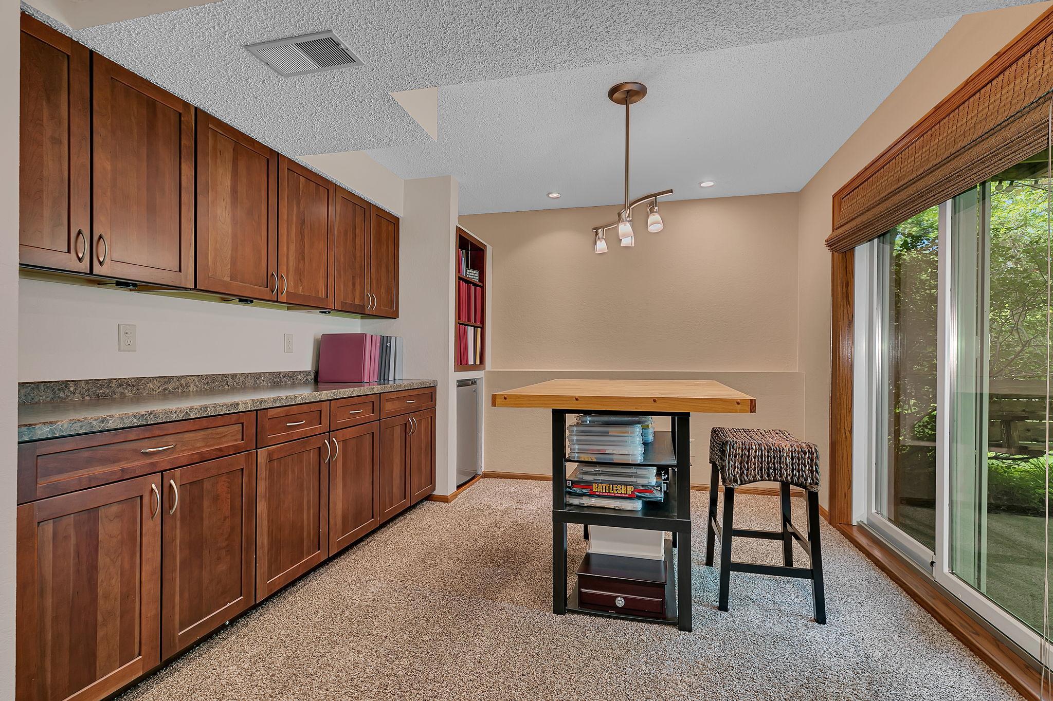 The lower-level flex space off the living room features countertop space, a built-in mini fridge area, storage, and a walkout to the backyard, making it the perfect spot for entertaining or creating a space that fits your needs.