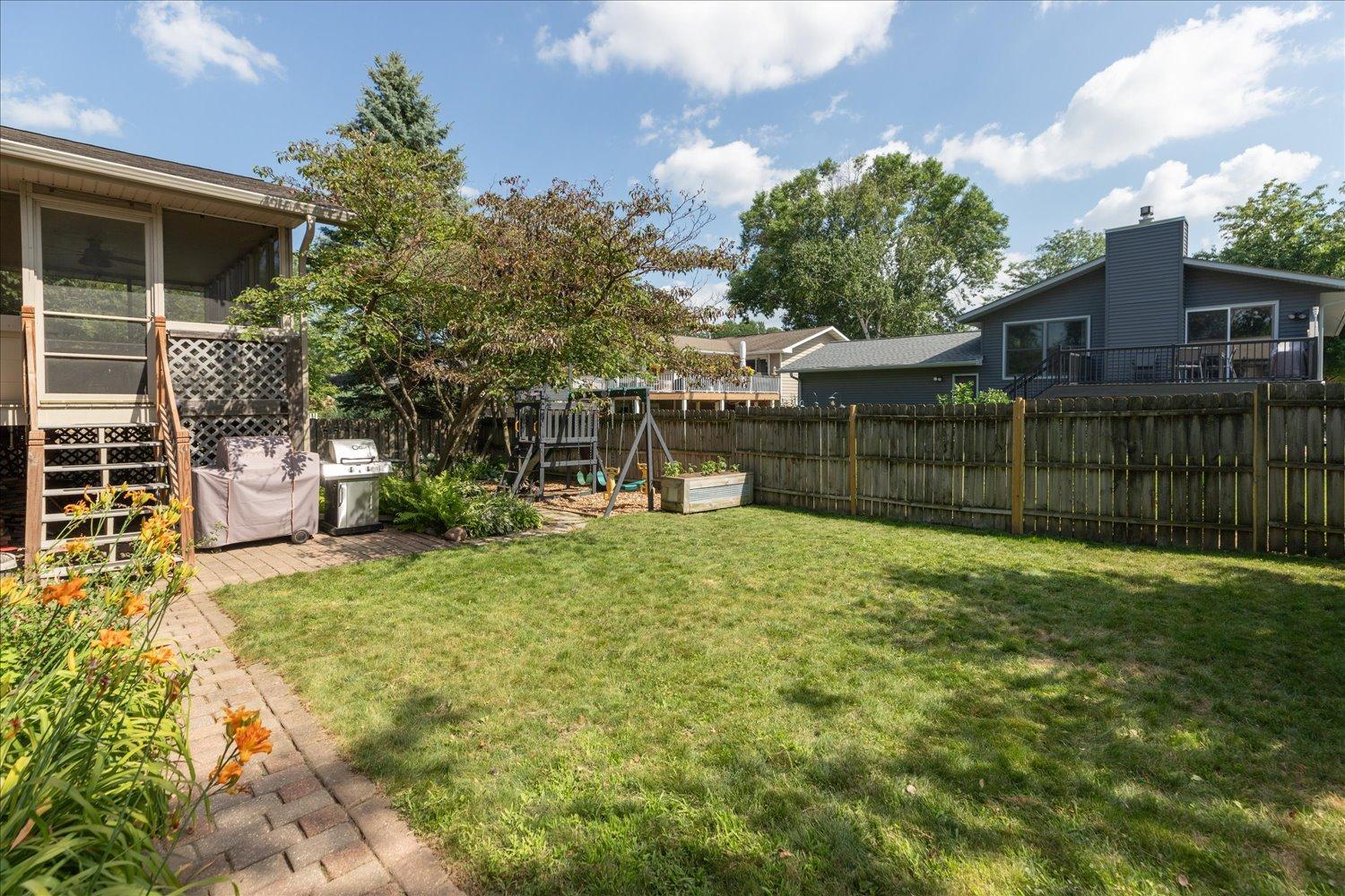 Fenced in back yard filled with trees for shade and privacy