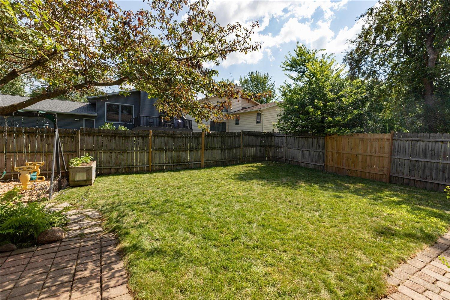 Fenced in back yard filled with plenty of green space