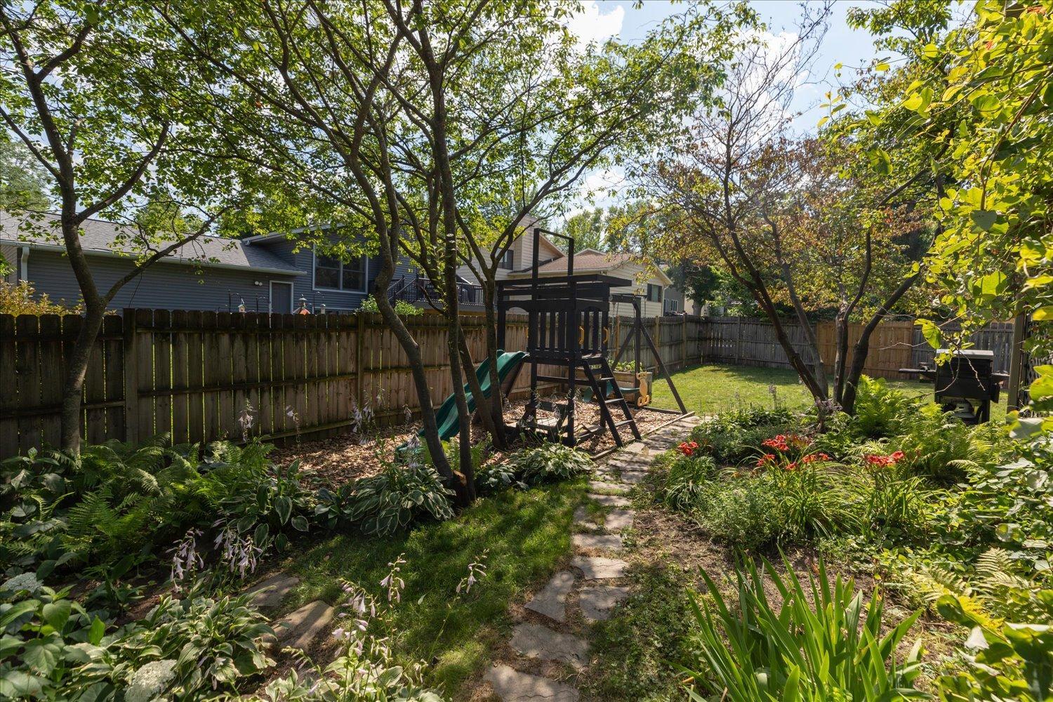 Fenced in back yard filled with trees for shade and privacy