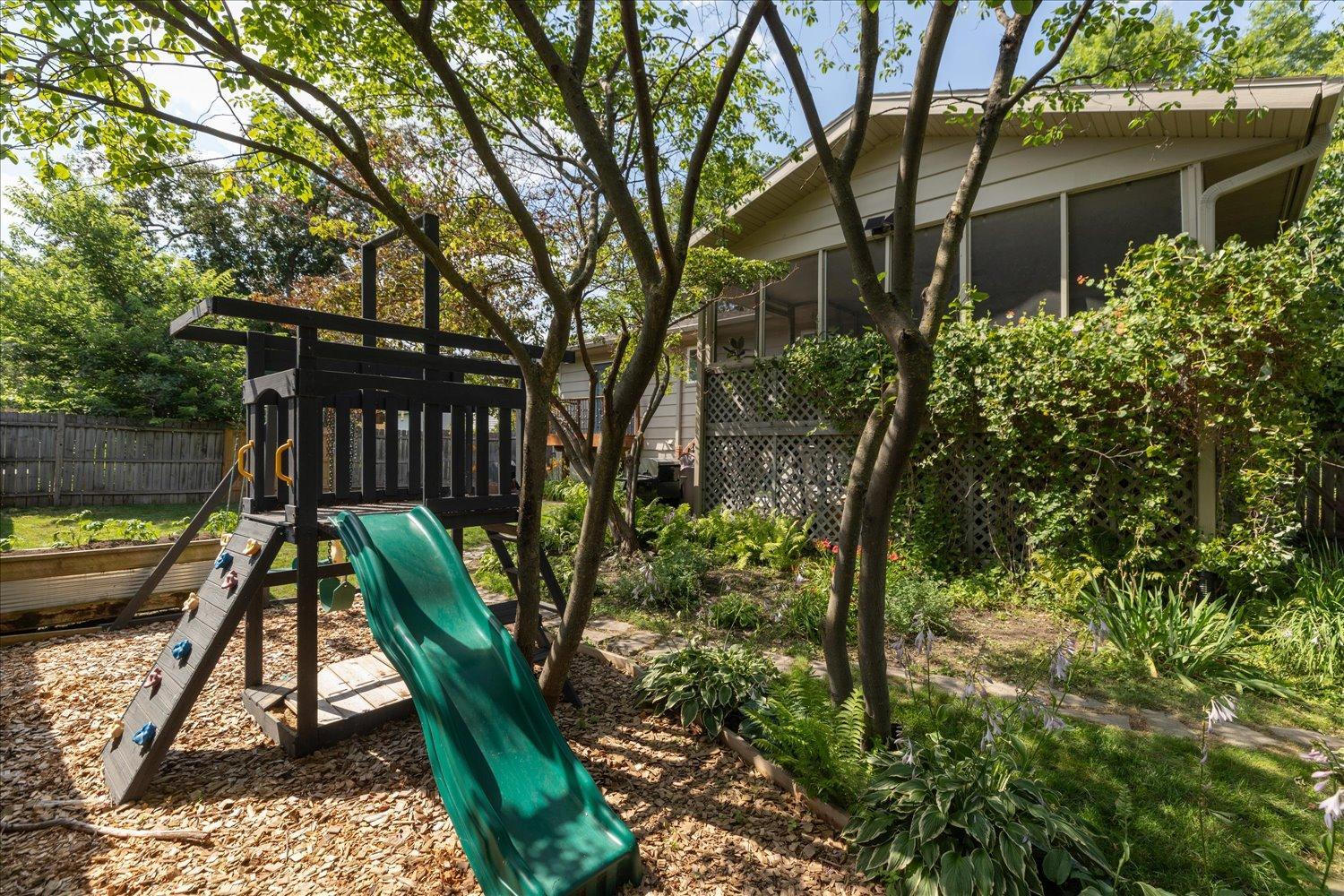 Fenced in back yard filled with trees for shade and privacy
