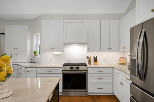 Eye catching gold hardware knobs and pulls, slide in gas range and under cabinet lighting