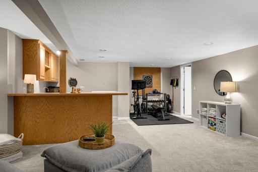 Lower level family room and bar with overhang for seating. Additional niche used as workout space.
