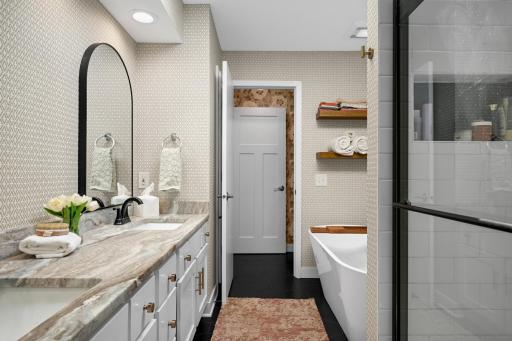 Striking main floor bath remodel offers dual sinks with honed granite, charcoal tile floors and custom tile shower.