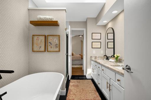 Remodeled bath offers free standing soaking tub with separate custom tiled shower and matt black hardware accents