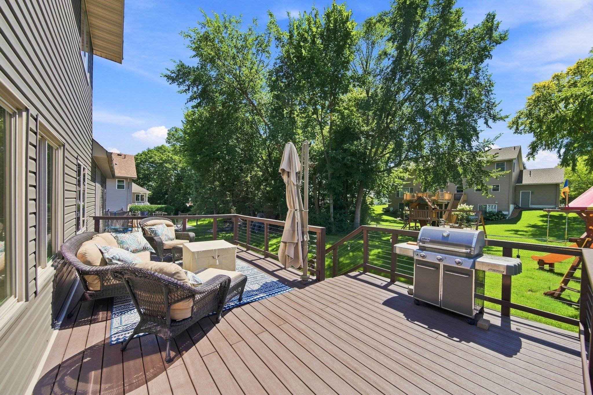 This spacious, maintenance-free outdoor deck offers plenty of room for a grill, seating area, and built-in umbrella, with see-through railing that provides a clear view of pets and children playing in the fenced yard.
