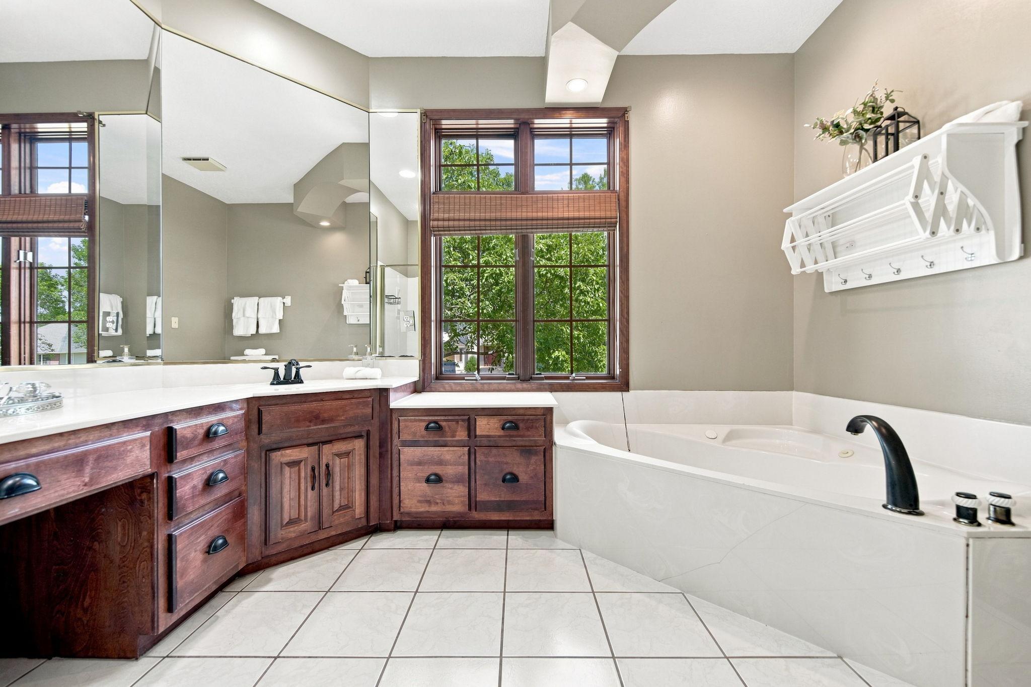 This expansive main floor primary bath features dual sinks, a jetted tub, a hanging rack for drying clothes, and a generously sized shower.