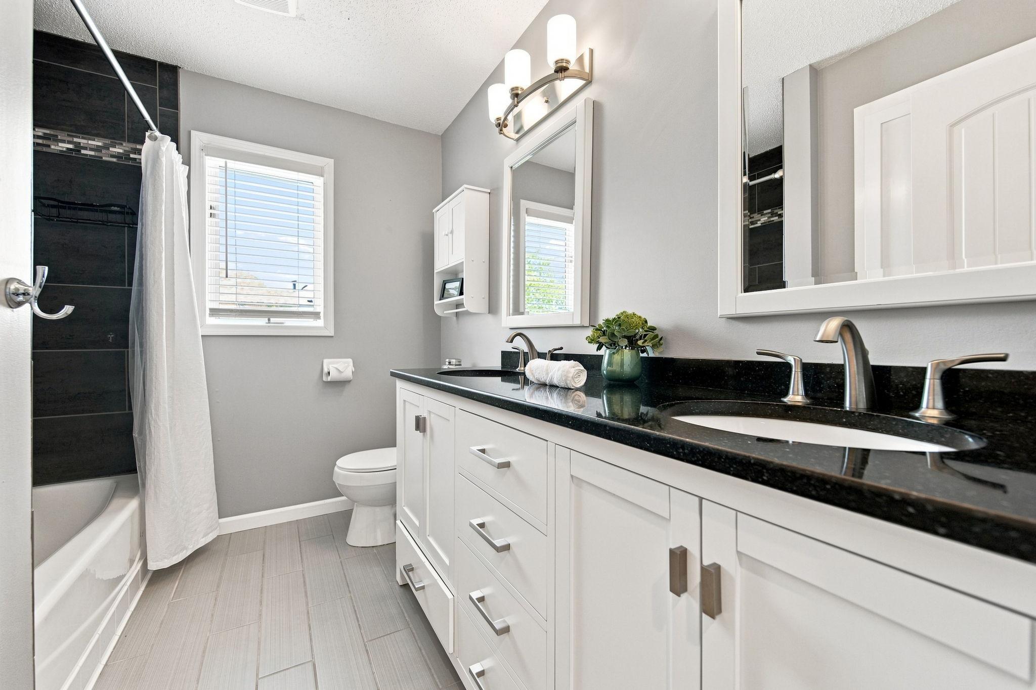 This upper-level full bathroom features double sinks, white cabinetry, and a convenient tub/shower combo.