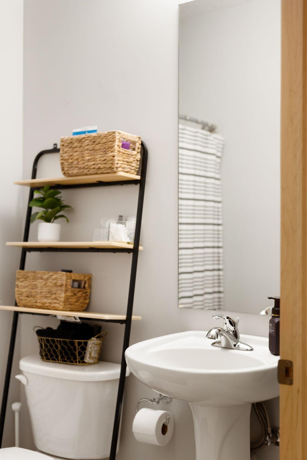 Stylish bath detail featuring a pedestal sink, tall mirror, and added storage.