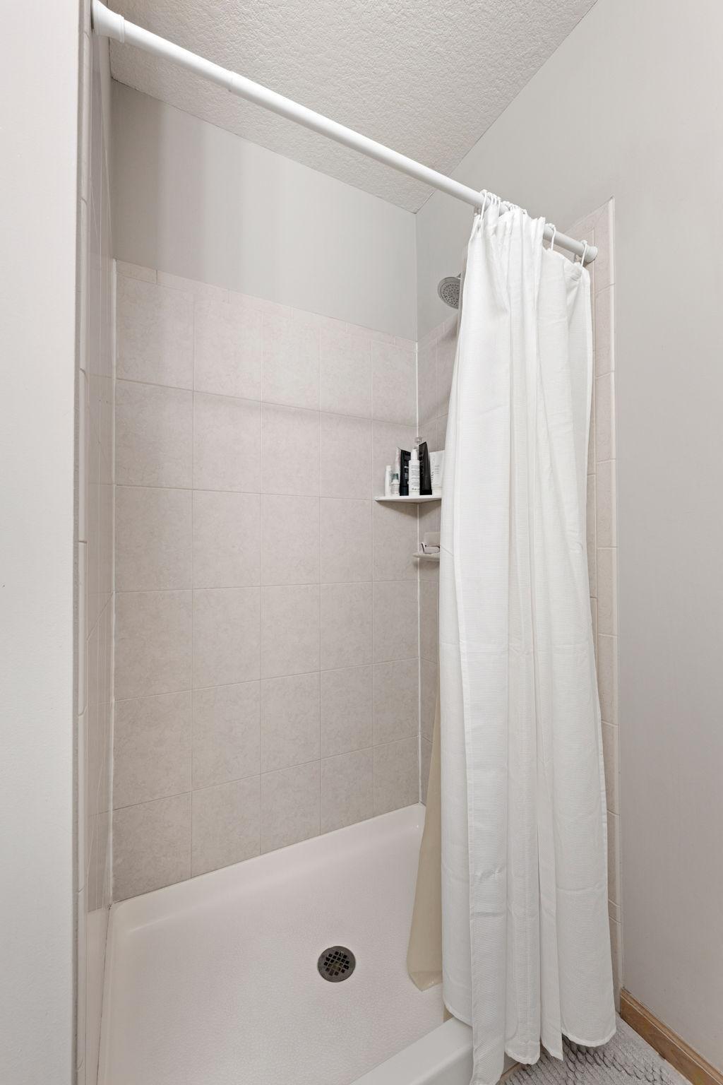 Walk-in shower in the private primary bath with neutral tile finishes.