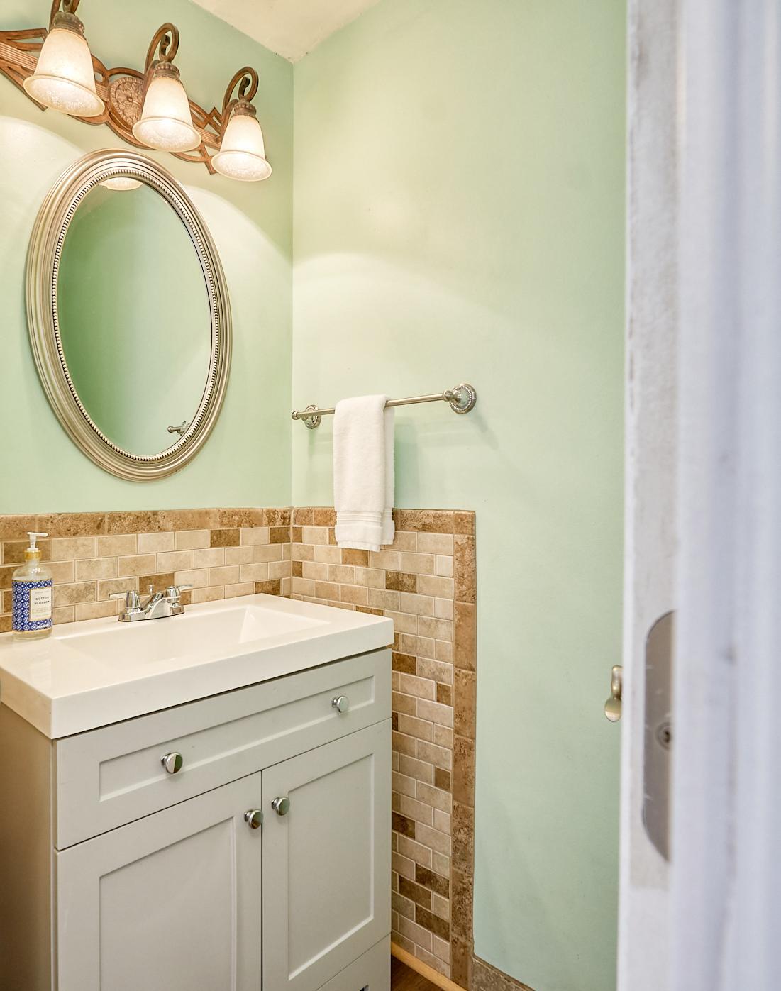 Main-floor half bathroom with tile & new vanity.