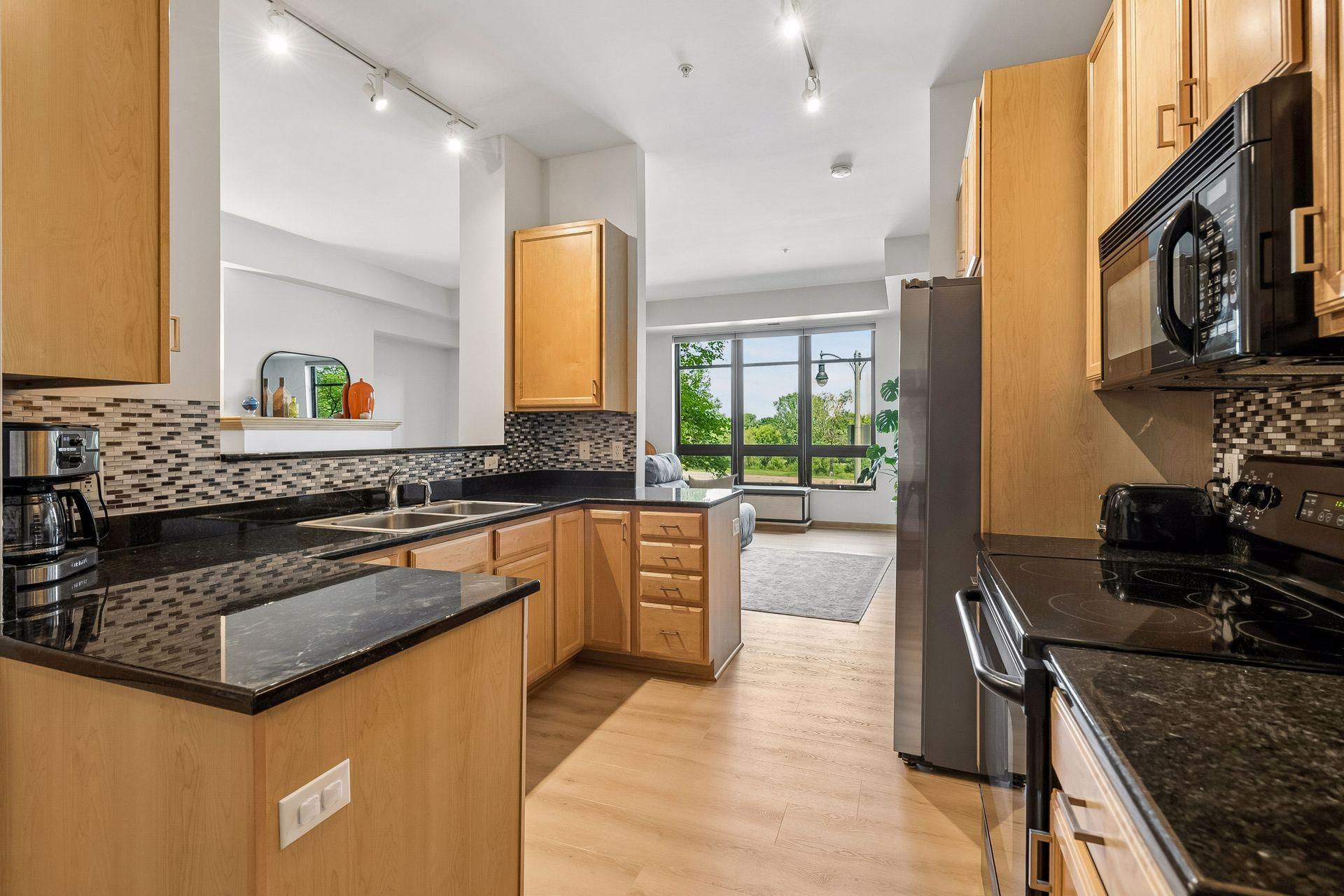 The kitchen has black granite tops and lots of natural light. You can see the fireplace through this opening.
