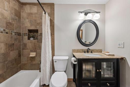 Ensuite bath with tile-surround tub and vanity with granite counter.