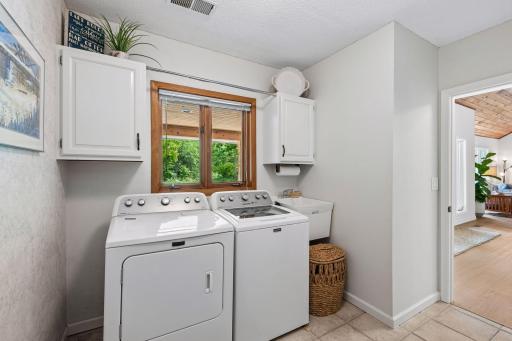 Main-level laundry with a utility sink and storage.