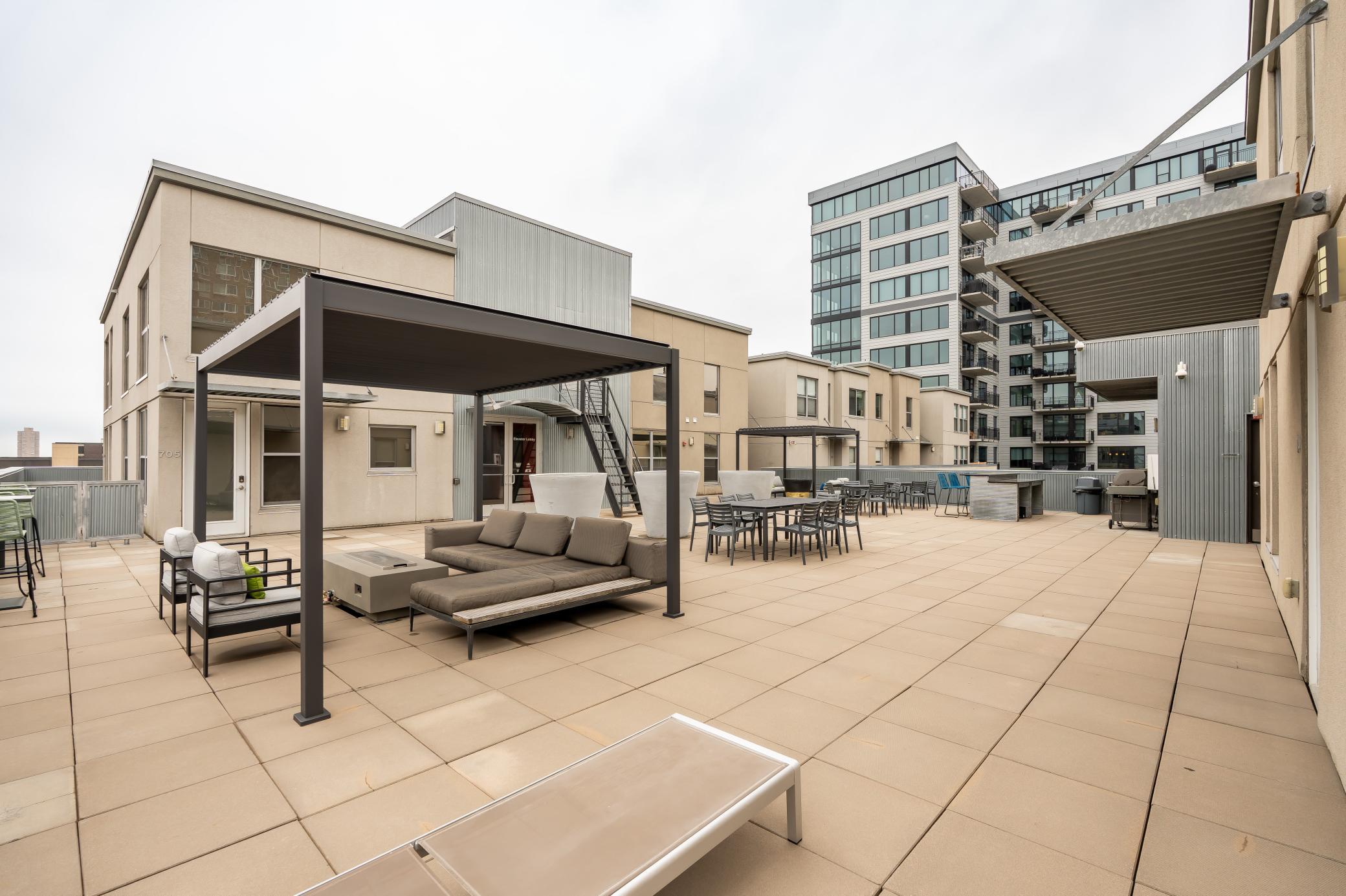 Incredible rooftop deck offers entertaining space with multiple lounge areas, dining setups, grilling station, and panoramic downtown skyline views.