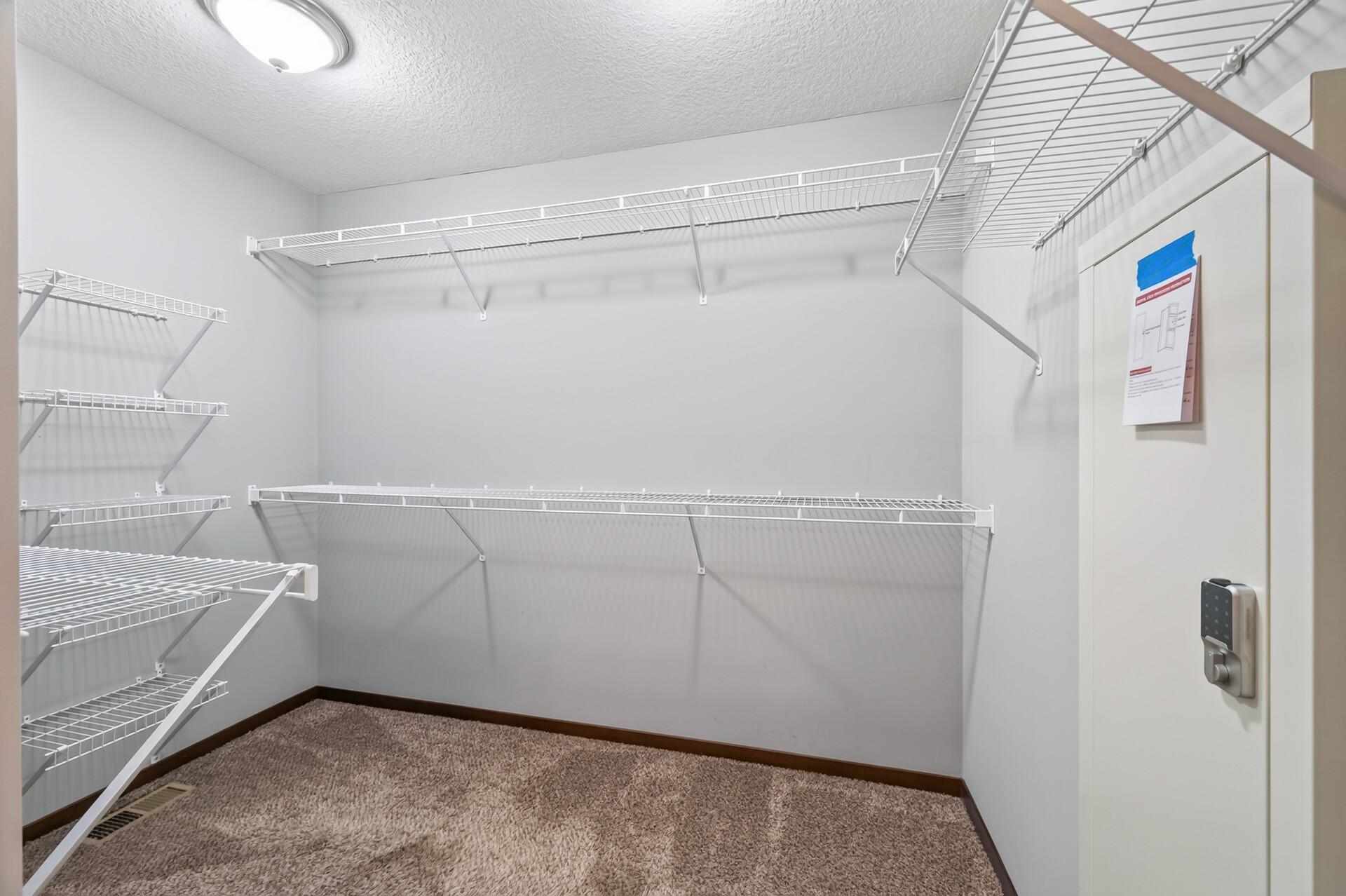Upper level primary bedroom walk-in closet with custom built-in gun safe