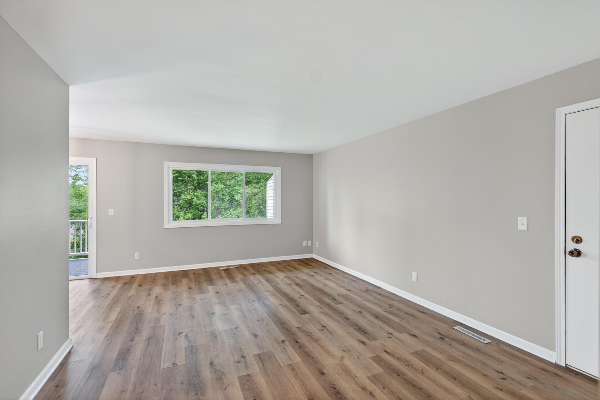 Bright and spacious living room with large picture window and deck access.