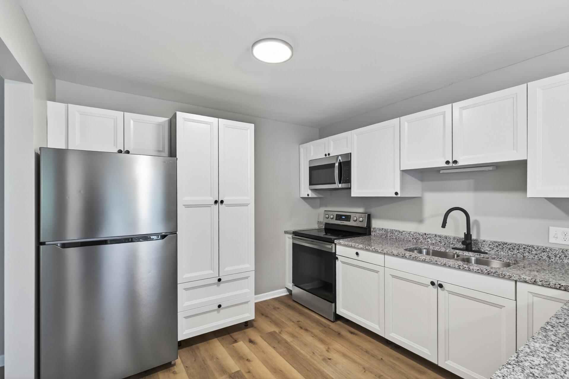 Updated kitchen featuring white cabinetry, stainless steel appliances, and abundant storage.