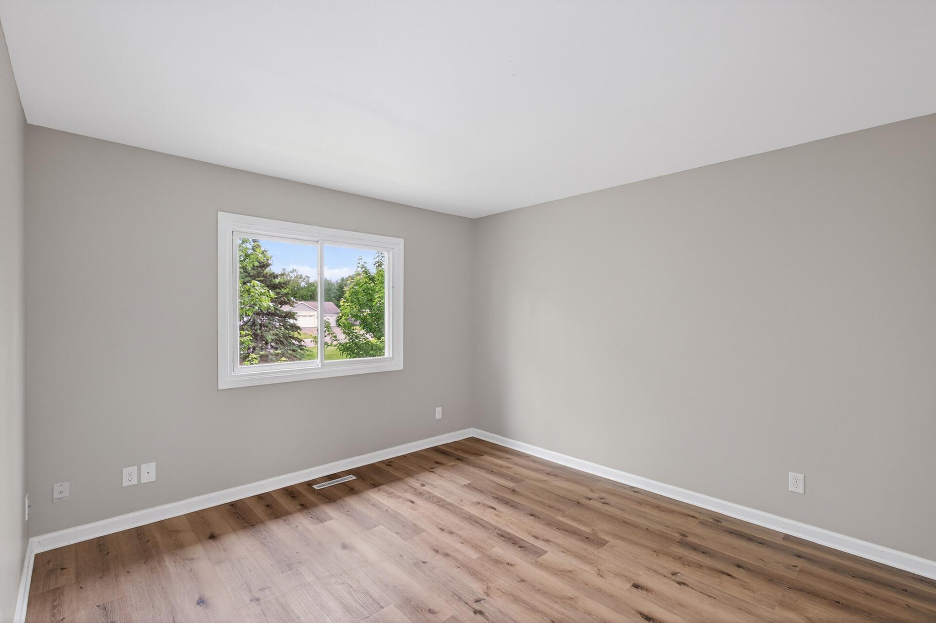 Bright guest bedroom with neutral finishes and updated flooring.