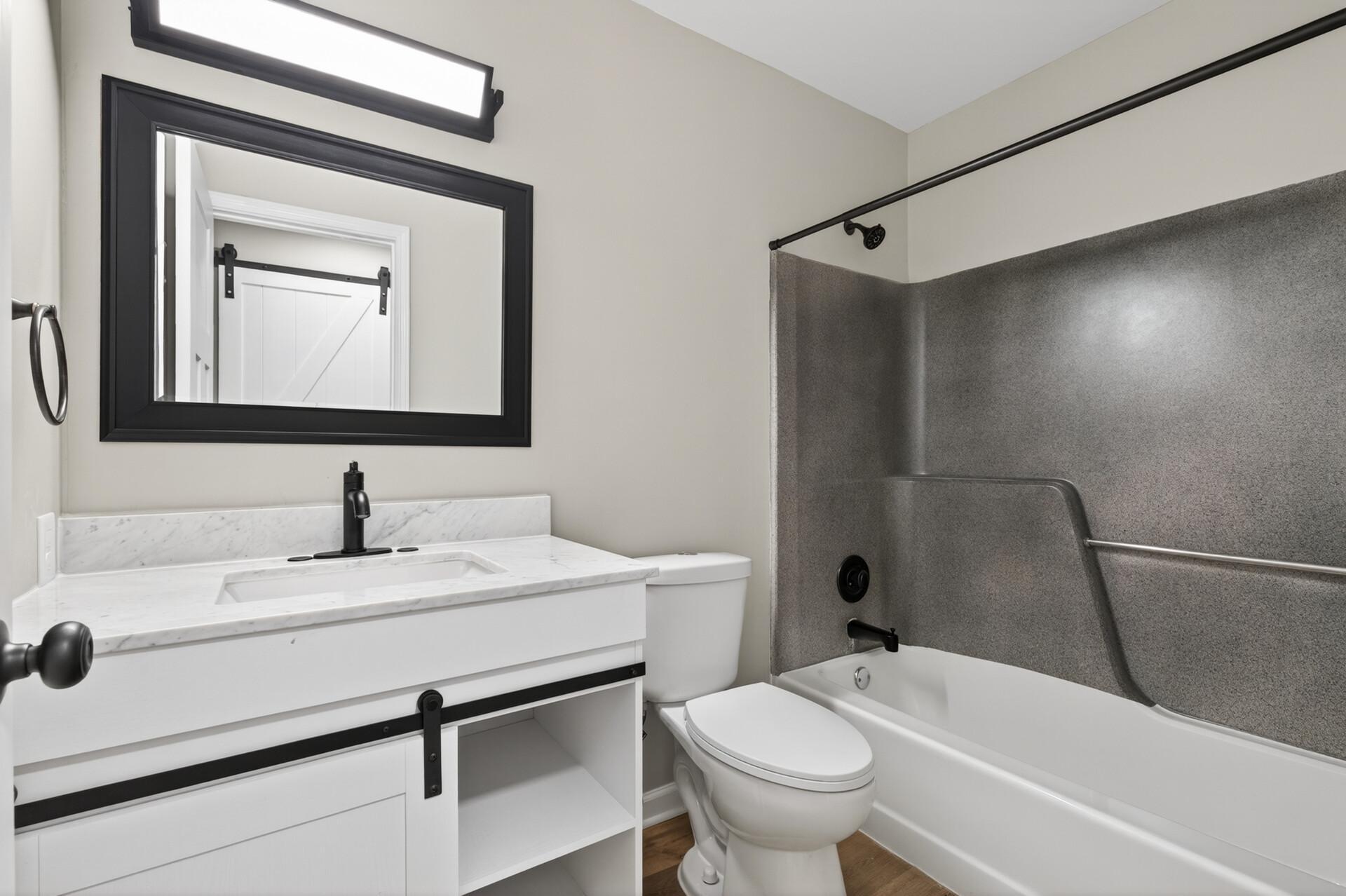 Full bath featuring updated vanity, modern lighting, and tub/shower combo.