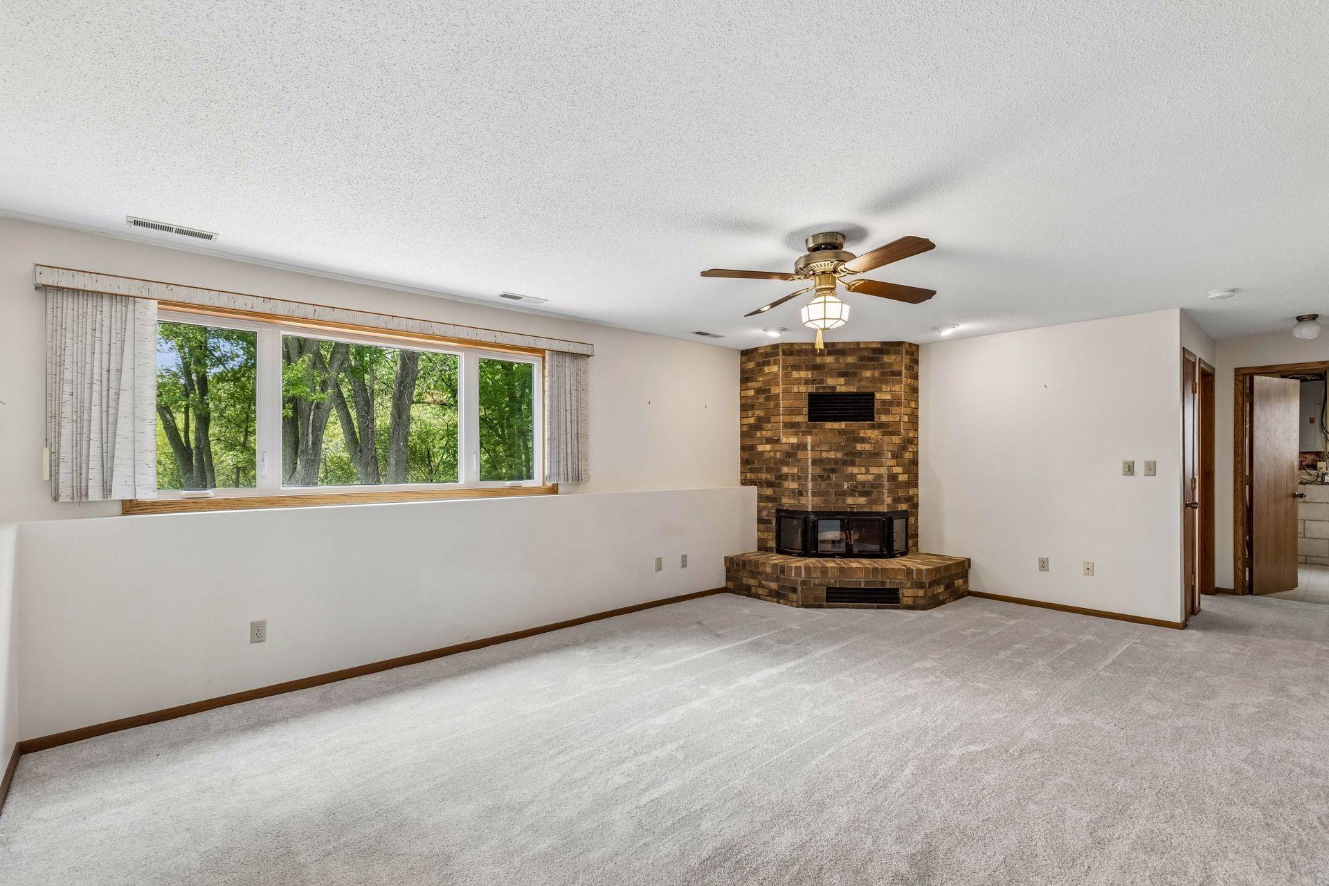 Lower level family room with expansive picture window and brick wood burning fireplace.