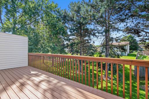 The deck overlooks the green area for a relaxing spot.