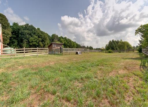 Paddock and riding arena adjacent to dry lot. Fenced garden on far end.