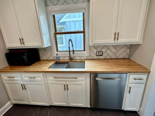 Bright, updated kitchen featuring warm wood countertops, crisp white Shaker cabinetry, and premium stainless steel appliances.