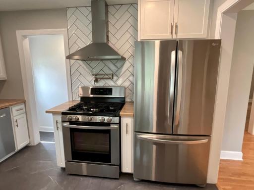 Sleek stainless steel appliances, a convenient pot filler faucet, a stylish tile backsplash, and a modern statement range hood.