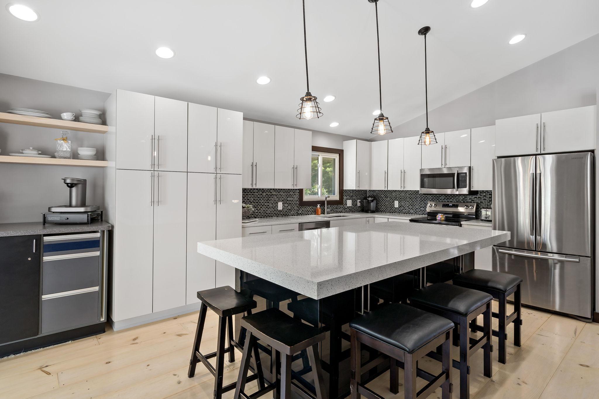 The kitchen remodel is an entertainer's dream with sleek acrylic cabinetry, stainless steel appliances, HUGE island with 5" thick Cambria countertops, and more storage than you'll know what to do with!