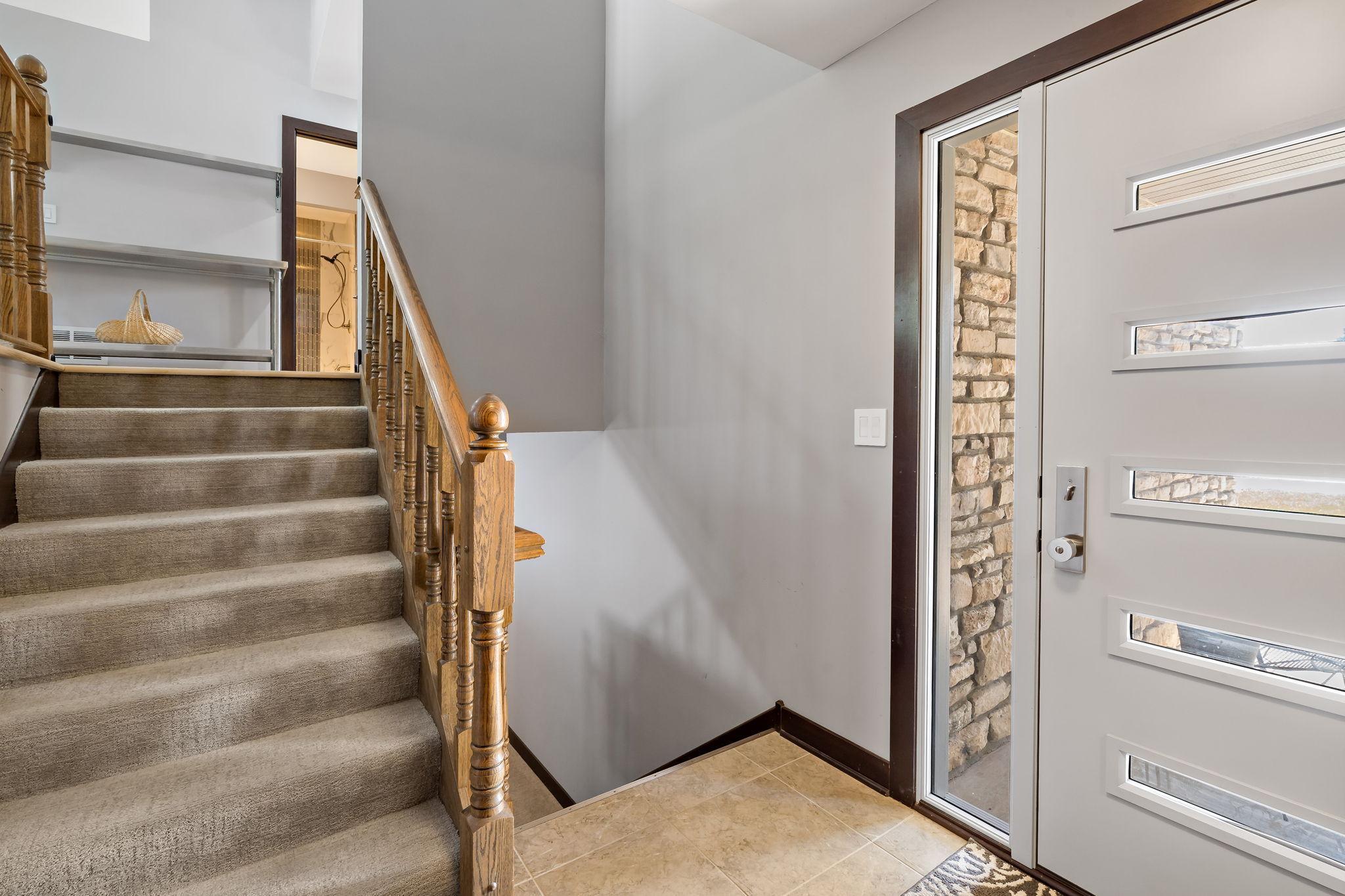 5 panel steel door, 12" sidelite, and ceramic tile flooring featured in the foyer