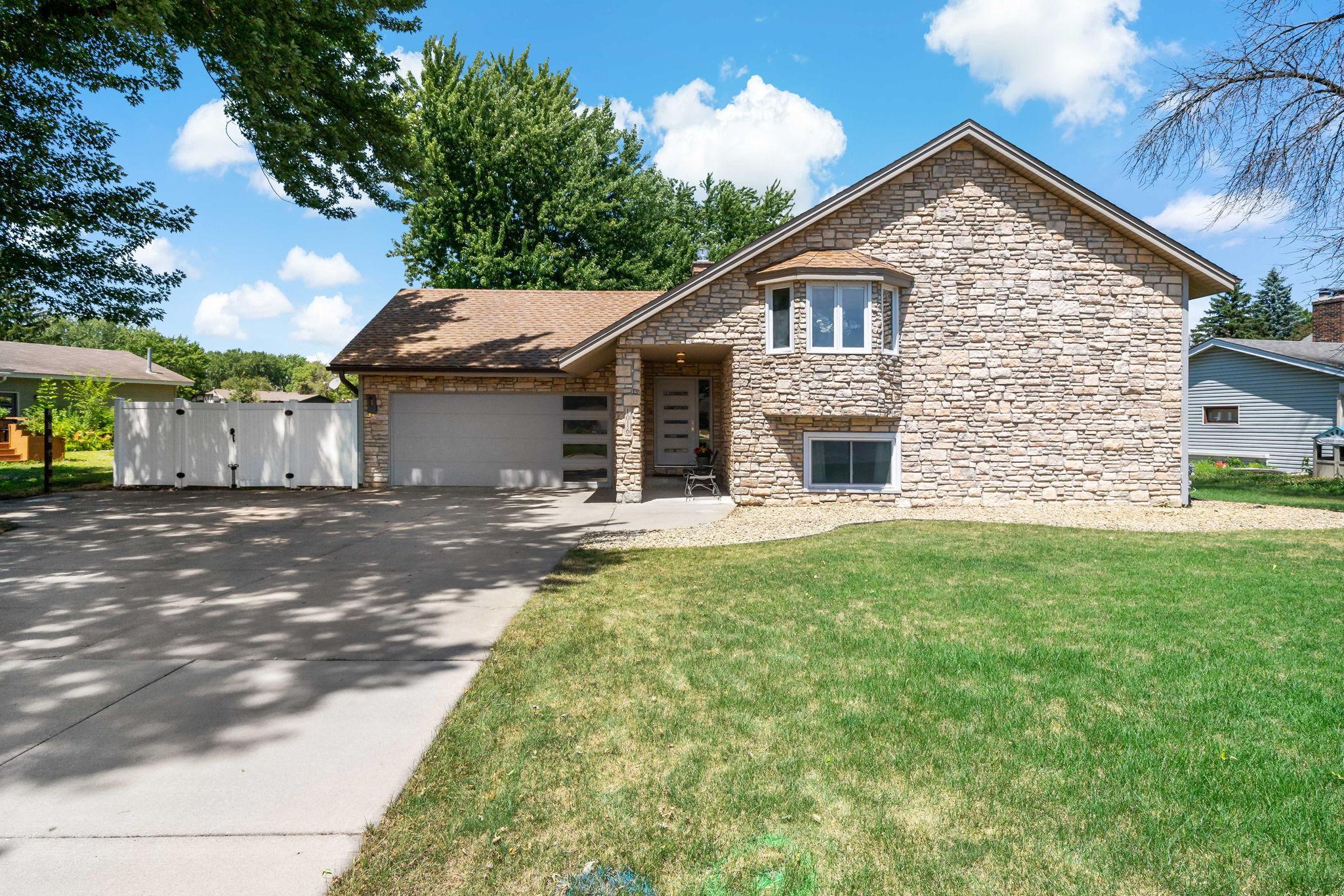 The welcoming front elevation features a full stone facade and contemporary garage and front doors