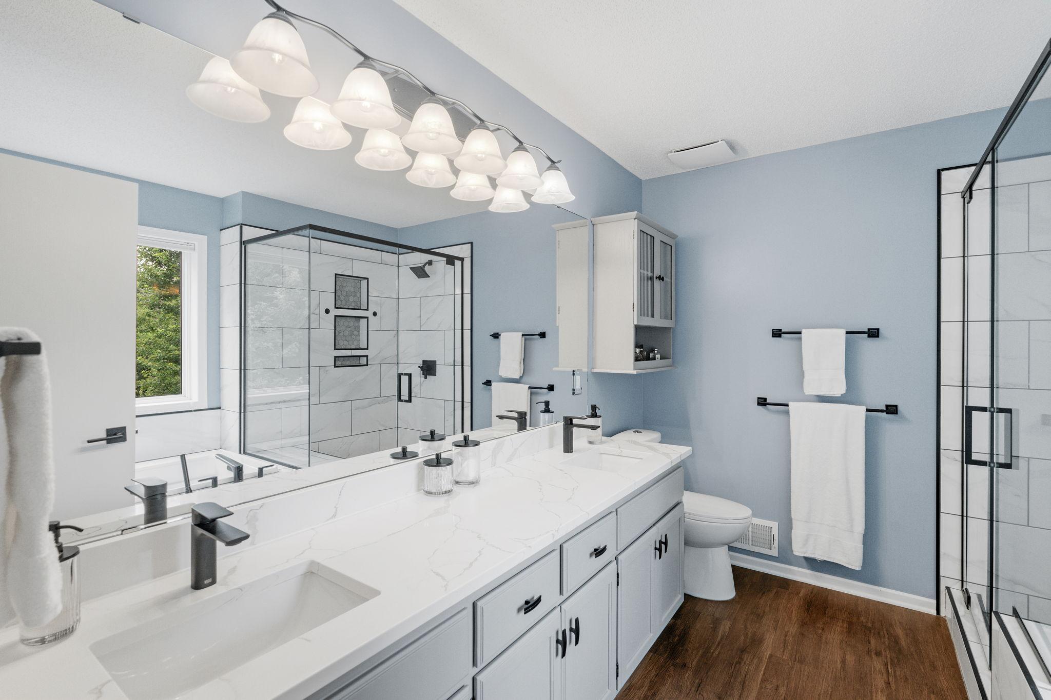Upper level private primary bathroom with quartz vanity countertop