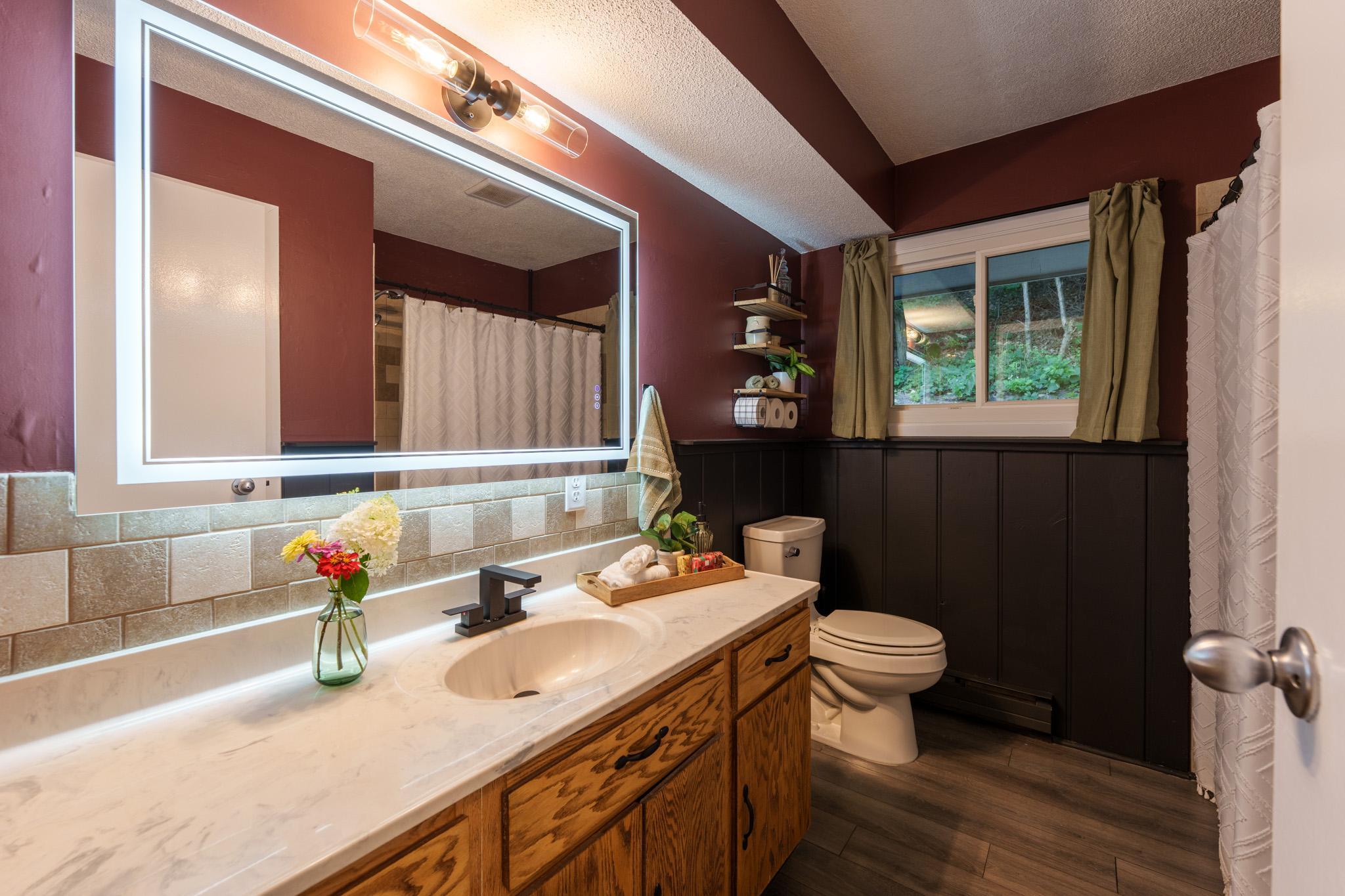 Full bathroom on the upper level with a refinished vanity, new mirror & lighting, fresh paint, closet shelving & tile shower.