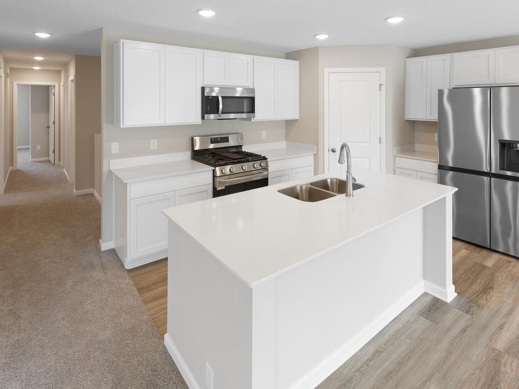 Kitchen. Photo taken of another home with similar plan and finishes. Photos and renderings may not depict actual plan, materials, & finishes may vary. All measurements are approximate.