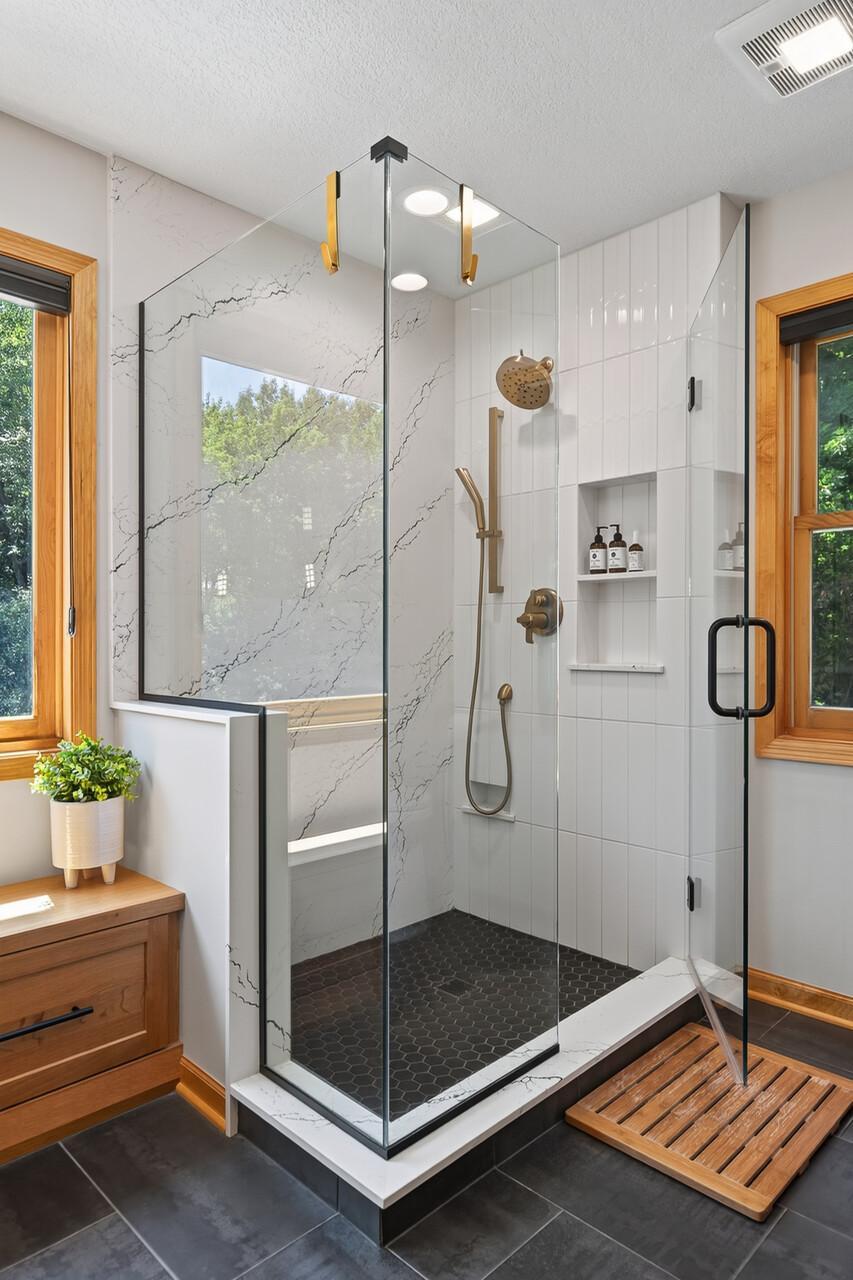 This floor-to-ceiling custom tiled shower with stunning gold accents and a sleek glass surround is nothing short of spectacular; the kind of shower that makes you never want to leave.