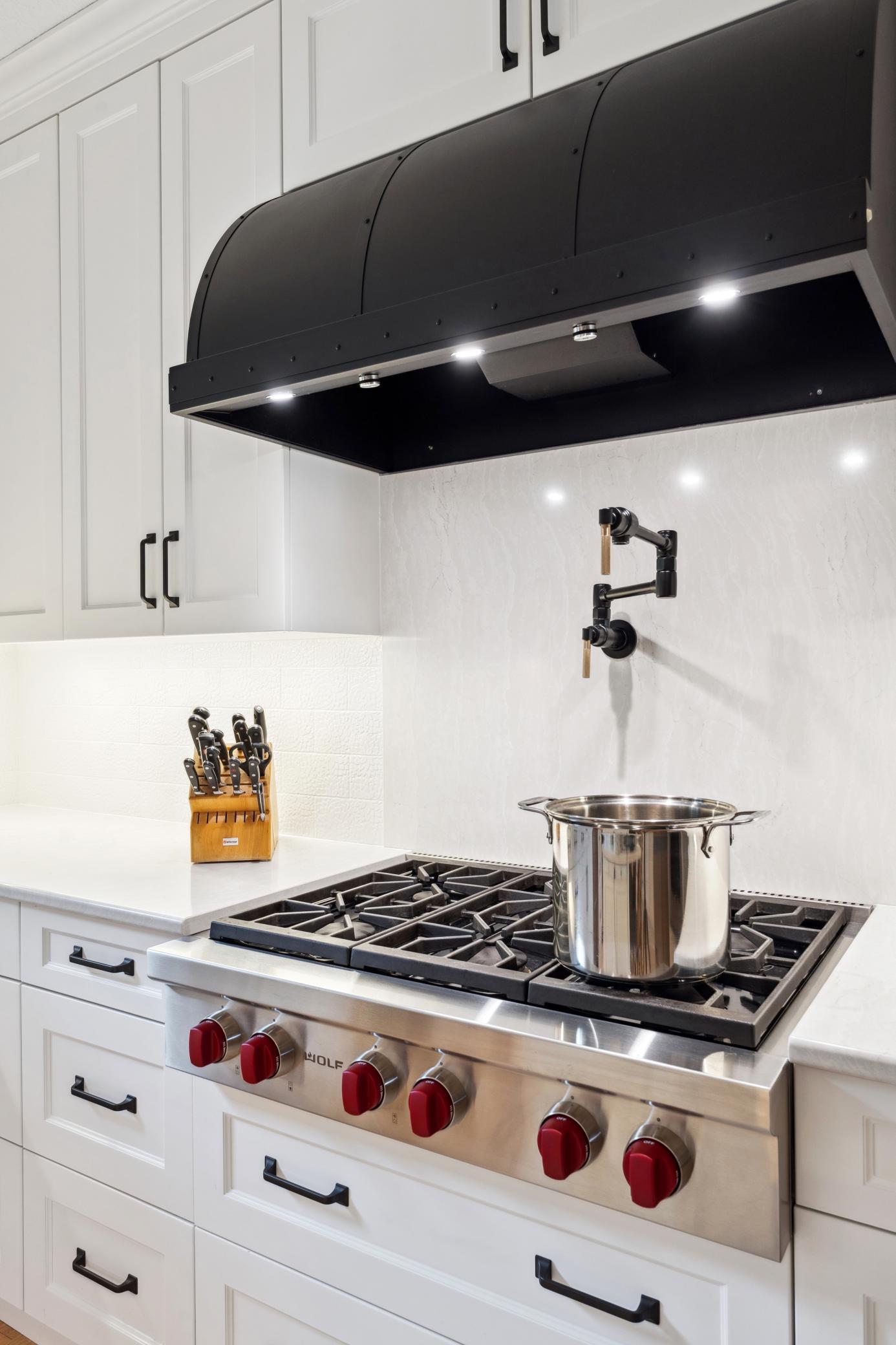 Wolf gas cooktop. Pot filler. Need we say more? This kitchen means business. Stunning hood vent steals the show.