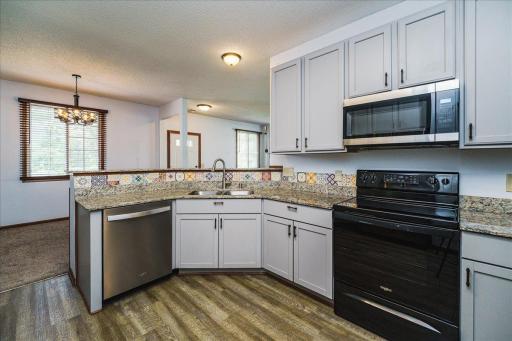 Kitchen features granite countertops, enameled cabinetry w/ 42" uppers, stainless steel appliances and a raised breakfast bar.