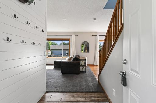 Extended tile entry way with shiplap wall of hooks to keep coats and backpacks organized.